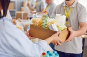 Volunteer at a food bank handing a box of food to a customer